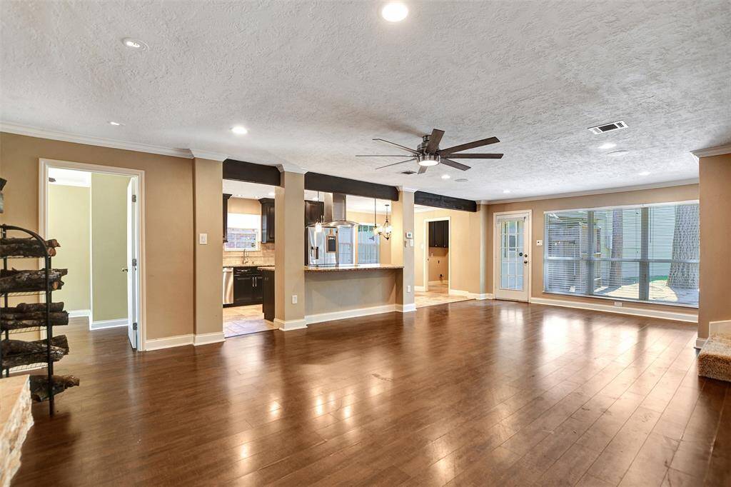 Spacious open-concept living area with natural light that fills the room, highlighting the warm, neutral walls. A door leads to an outdoor area.