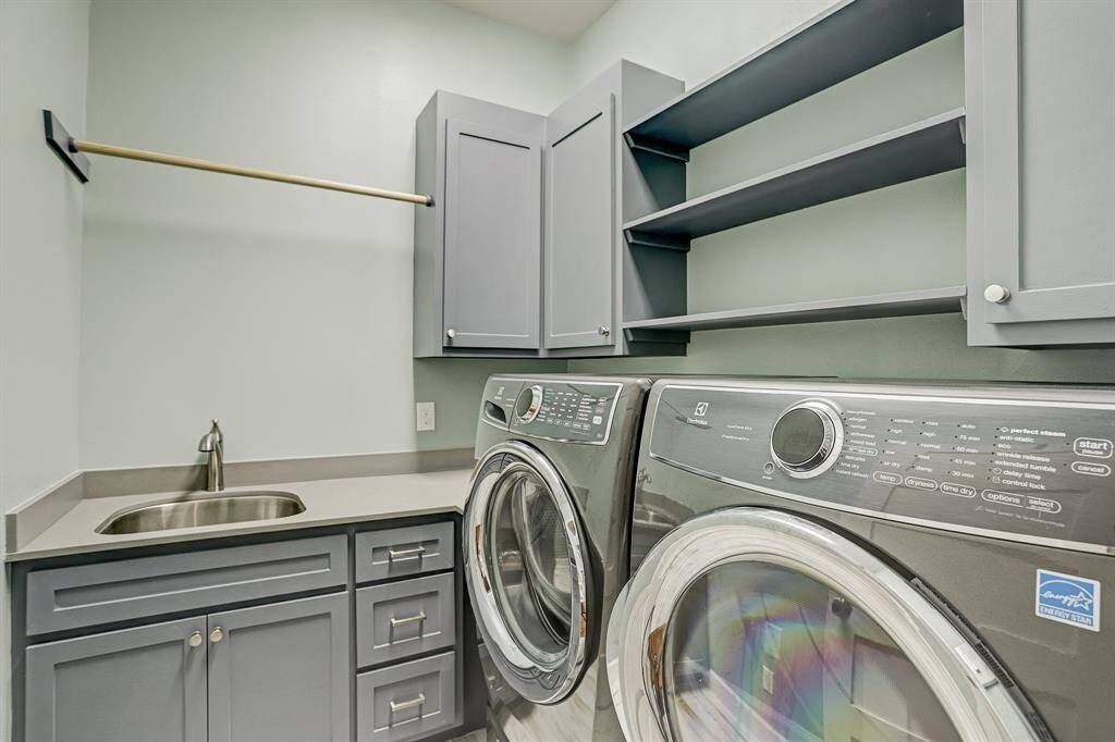 The centrally located laundry room has wood look tile floors, quartz countertop with stainless steel sink, cabinetry, and a hanging rod. Washer and Dryer are included!