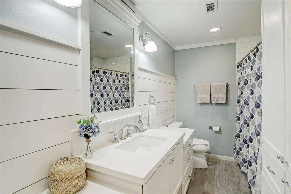 This secondary full bath is located in the hall to serve bedrooms 3 and 4. Quartz countertops, shiplap walls, and a tub with shower complete the space.