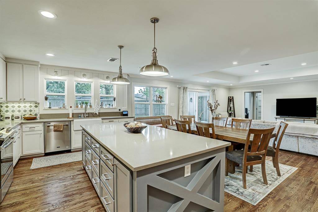 The farmhouse style kitchen has an oversized island with quartz countertop, farmhouse sink, pendant lighting, gas range, stainless steel appliances, and gorgeous tile backsplash. Refrigerator is included!