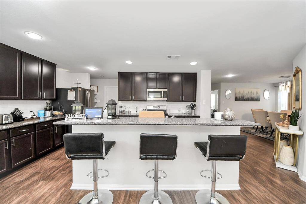Open-concept kitchen showcasing upper and lower cabinetry and granite counters