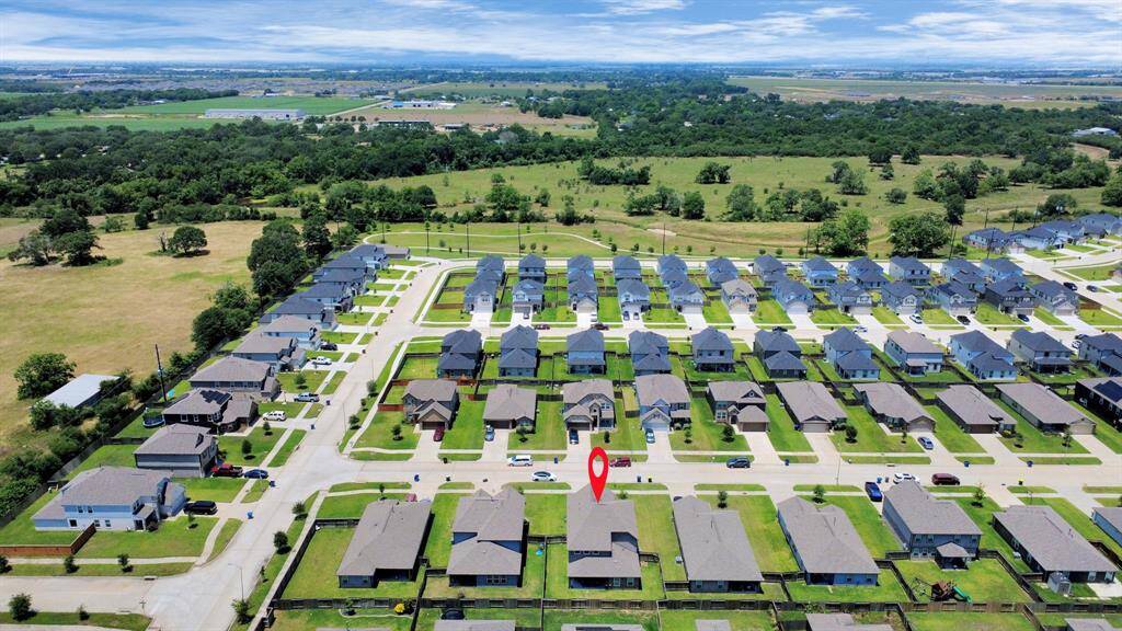 Wide-angle aerial shot showing the surrounding development and the home’s position in a growing community.