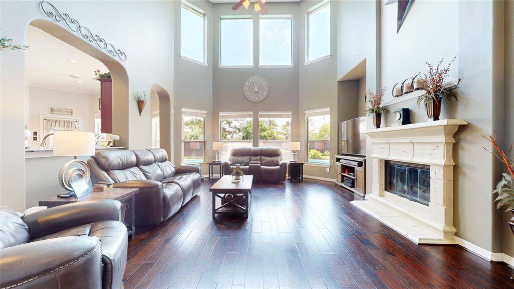 Step into the stunning family room featuring soaring ceilings that flood the space with natural light, creating an open and airy atmosphere. Freshly painted walls complement the rich hardwood floors, while the elegant fireplace and expansive windows offer both warmth and scenic backyard views. This beautifully designed space is perfect for relaxing evenings or entertaining guests, with seamless flow into the kitchen and dining areas.