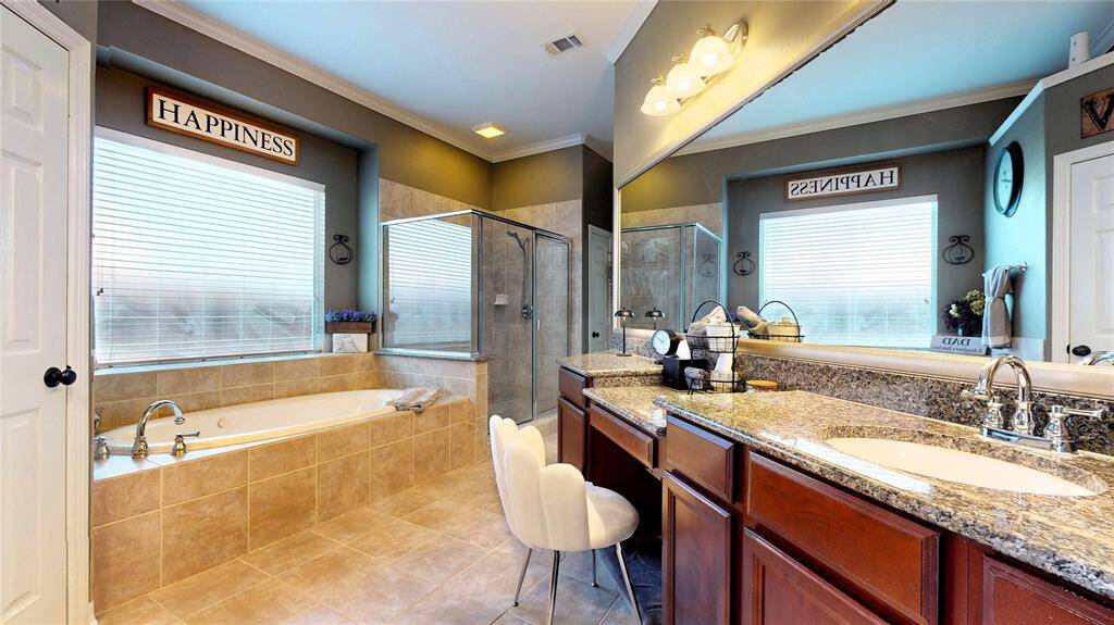 The ensuite bathroom is a spa-like escape with a large soaking tub, separate walk-in shower, and extended dual vanities with granite countertops and abundant cabinet space. A dedicated vanity area adds a touch of luxury. Two separate walk-in closets offer ample storage and organization, creating a truly functional and relaxing retreat.