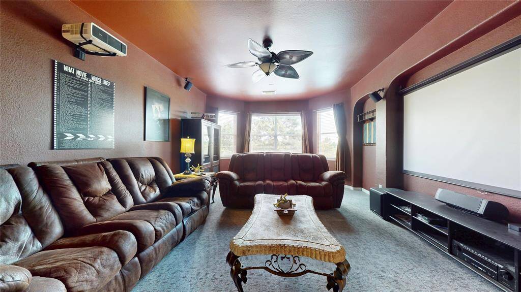 Step into your personal entertainment retreat! This spacious upstairs media/game room features a custom theater setup complete with a projector, mounted screen, and surround sound wiring—ideal for movie nights or immersive gaming experiences. Rich wall tones and plush carpeting create a cozy ambiance, while large windows bring in natural light when needed. French doors provide privacy without sacrificing style, and the space offers flexible use for family fun, relaxation, or entertaining guests.