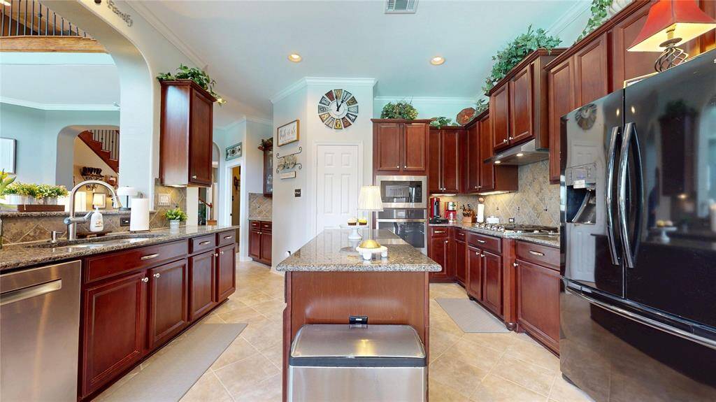 This beautifully appointed island kitchen offers both functionality and charm, featuring rich wood cabinetry, granite countertops, and a stylish tile backsplash.
