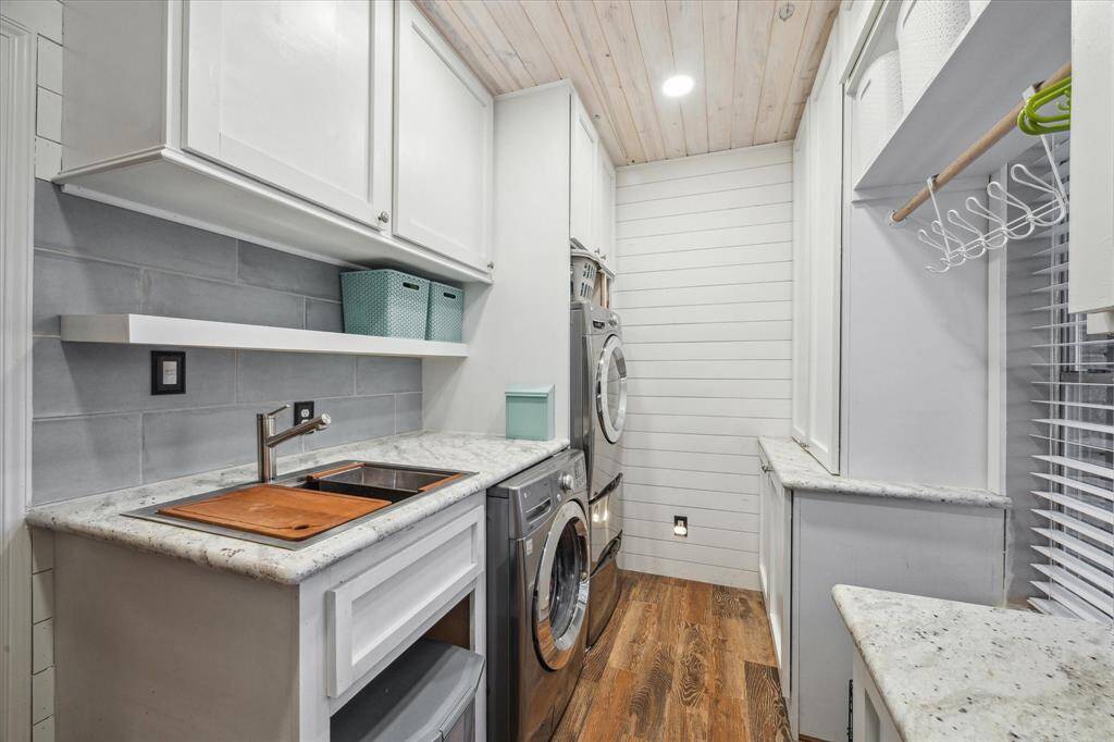 This well-organized laundry room features washer/dryer connections, upper storage cabinets, and space for folding and sorting. Durable flooring and practical layout make daily chores easier to manage.