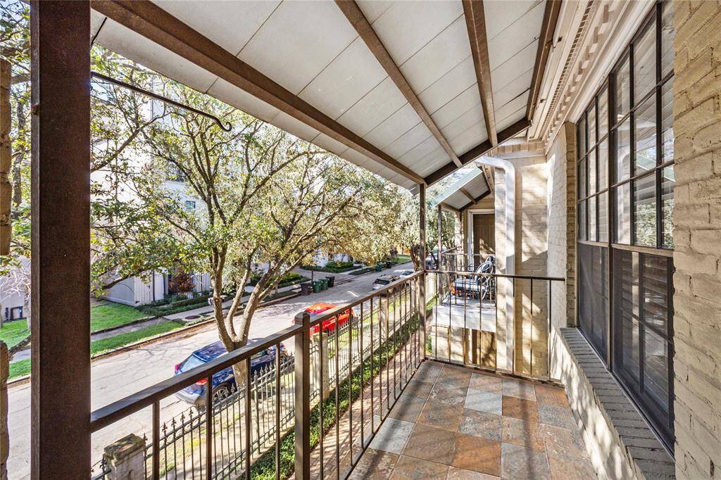 Enjoy fresh air and charming neighborhood views from this covered balcony with wrought iron railing and ample space for seating. *Tile was digitally cleaned and altered.
