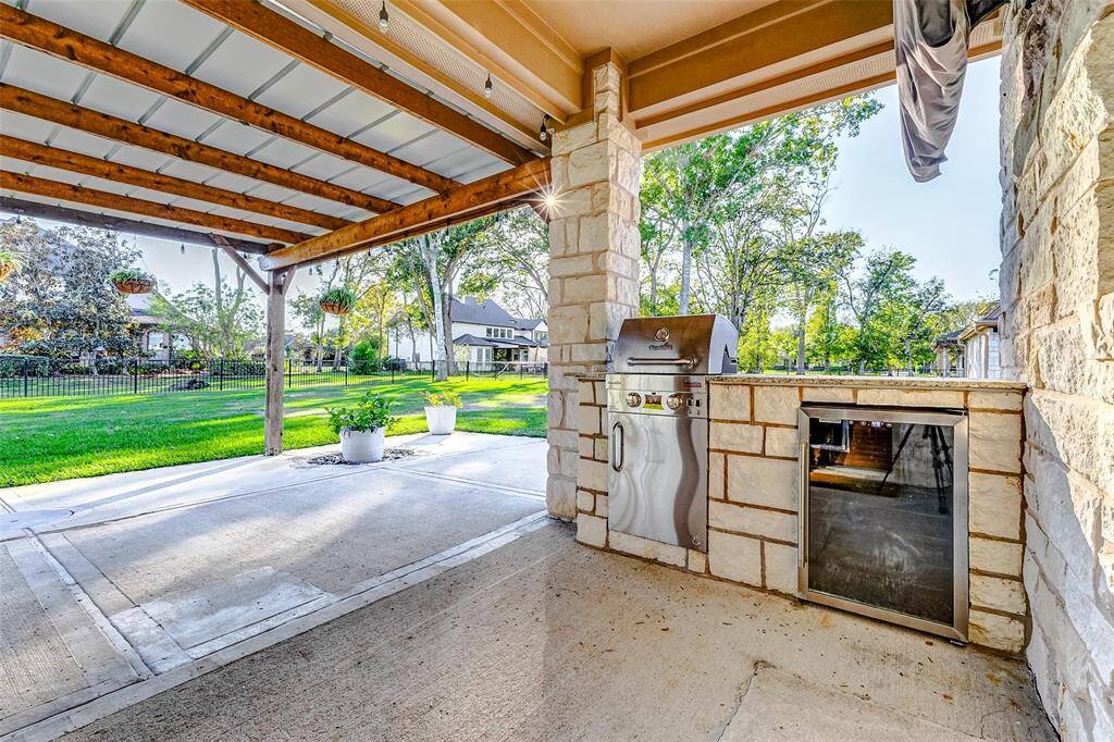 This luxurious outdoor kitchen is a chef's dream. The built-in grill and mini-fridge make entertaining a breeze. The covered patio with stone columns creates a stylish and inviting space.