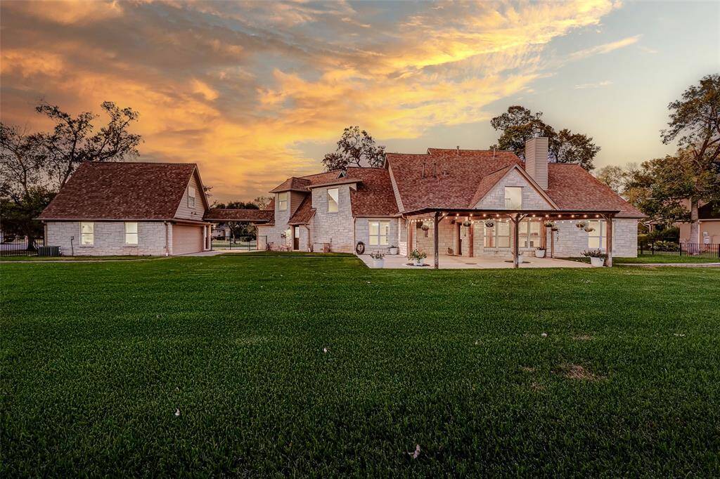 This idyllic setting showcases the timeless home with a distinctive roofline and a serene, expansive lawn. The breathtaking sunset sky creates a stunning contrast to the property's architecture!