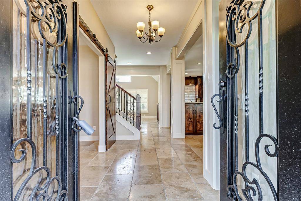 Step through these stunning grand iron doors and into a home refreshed with crisp, new paint. This elegant entryway sets the tone for a warm and inviting interior, blending timeless craftsmanship with modern updates. A perfect first impression awaits!