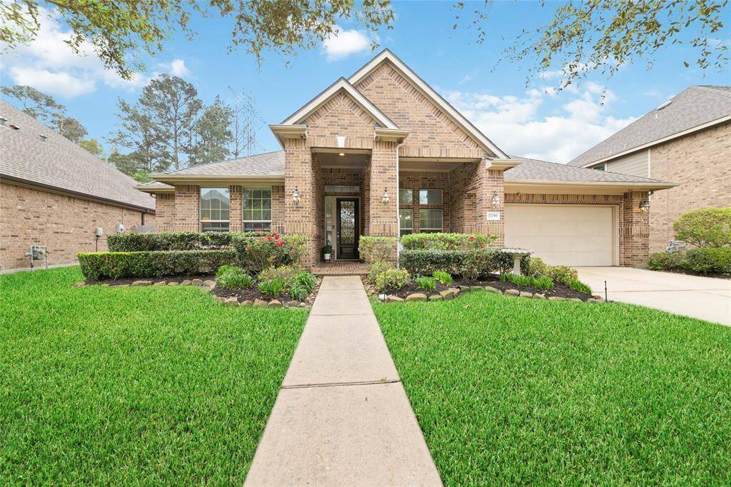 This inviting brick home on all four sides features a well-maintained front yard with lush green grass and neatly arranged shrubs. It has a charming entrance with a covered porch and a three-car tandem garage.