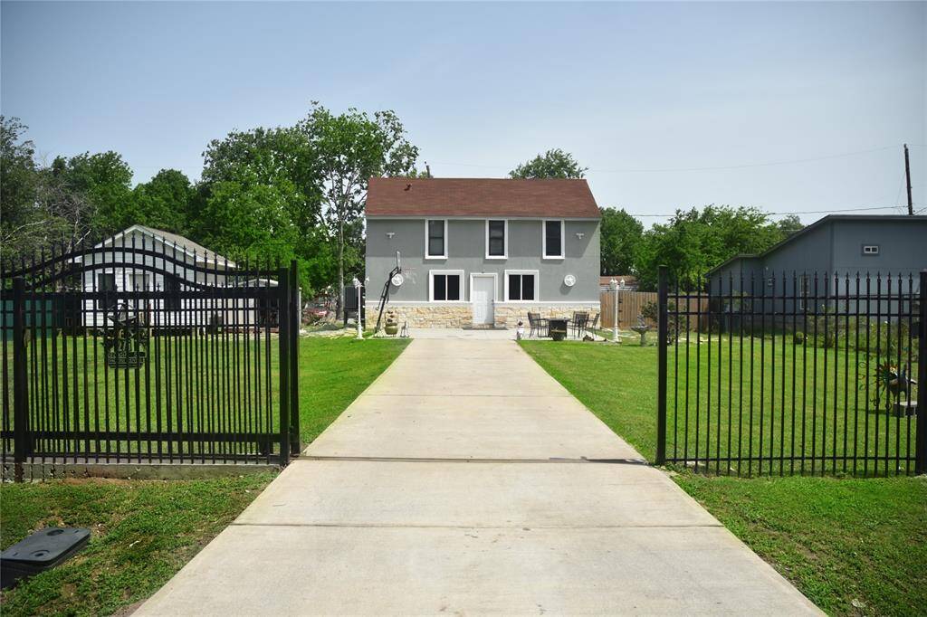 Experience tranquility in this charming two-story home. Set back on a long driveway behind a secure iron gate, it boasts a spacious front yard and mature trees, offering a serene, private retreat.