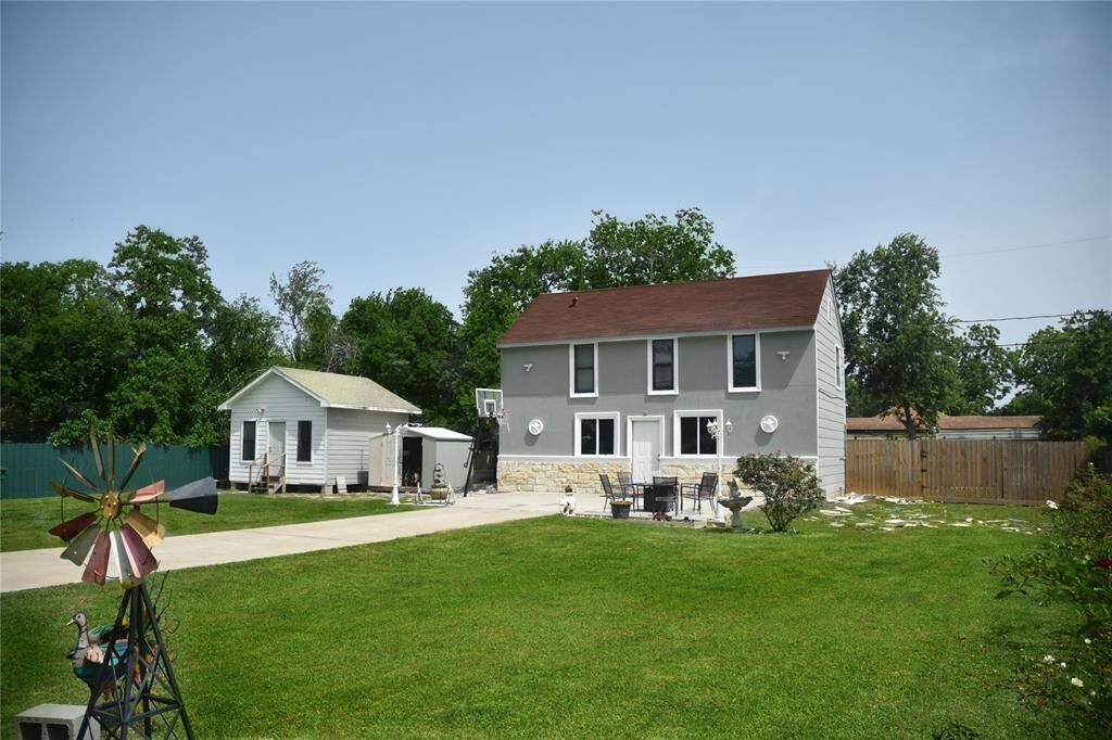 Generous green space framed by mature trees and gated entrance to front driveway.
