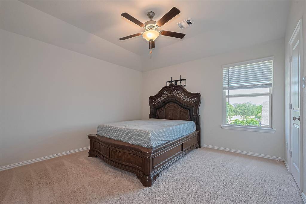 The spacious primary bedroom offers a peaceful escape, complete with plush carpeting, soft neutral tones, and abundant natural light streaming through large windows.