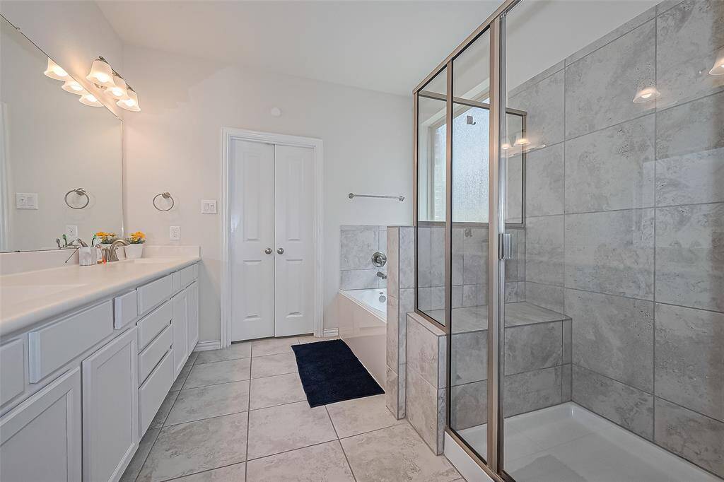 This spacious bathroom offers a perfect blend of functionality and style. Dual vanities provide ample space for two, while the separate walk-in shower adds convenience and modern appeal.