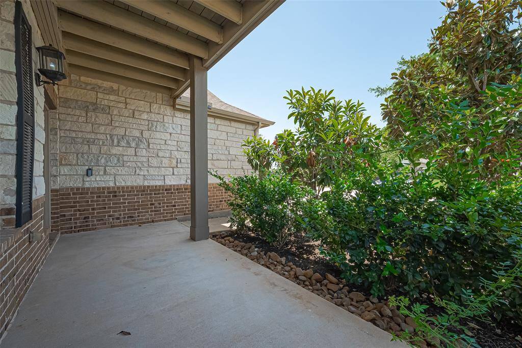 Begin your journey through the home with a warm and inviting entrance, framed by lush landscaping and a cozy front sitting area