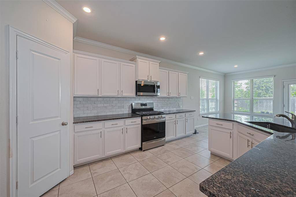 This open-concept kitchen is the centerpiece of the home, featuring gleaming stainless steel appliances, granite countertops, and crisp white cabinetry that provides a fresh and modern feel