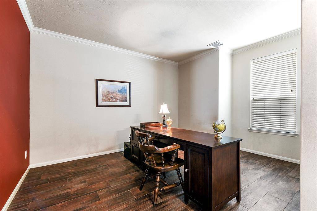 The large den/home office features the same luxury vinyl plank flooring that flows throughout the entire downstairs, creating a cohesive and elegant look. This spacious room is enhanced with crown molding and a window bump-out nook, providing an extra space.