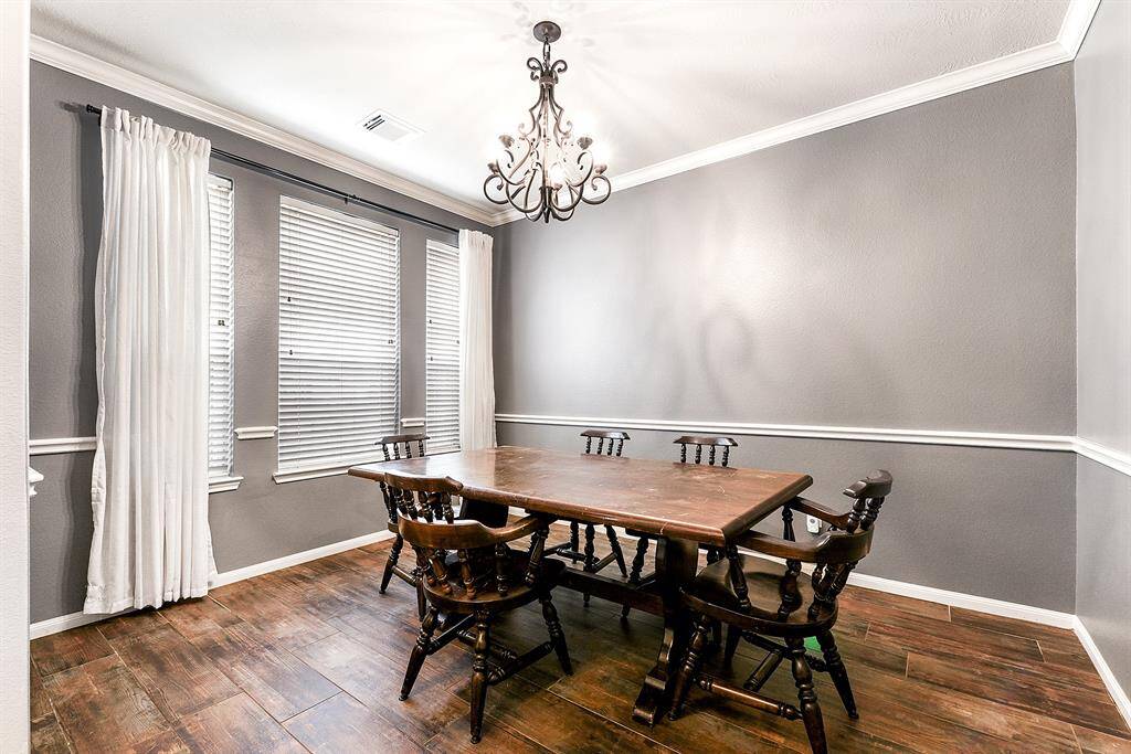 The formal dining room offers beautiful views of the front yard and is elegantly designed with a stunning hanging chandelier, crown molding, and the same luxury vinyl plank flooring that flows throughout the downstairs. This space creates the perfect setting for dinner parties and special gatherings, combining style and comfort seamlessly.