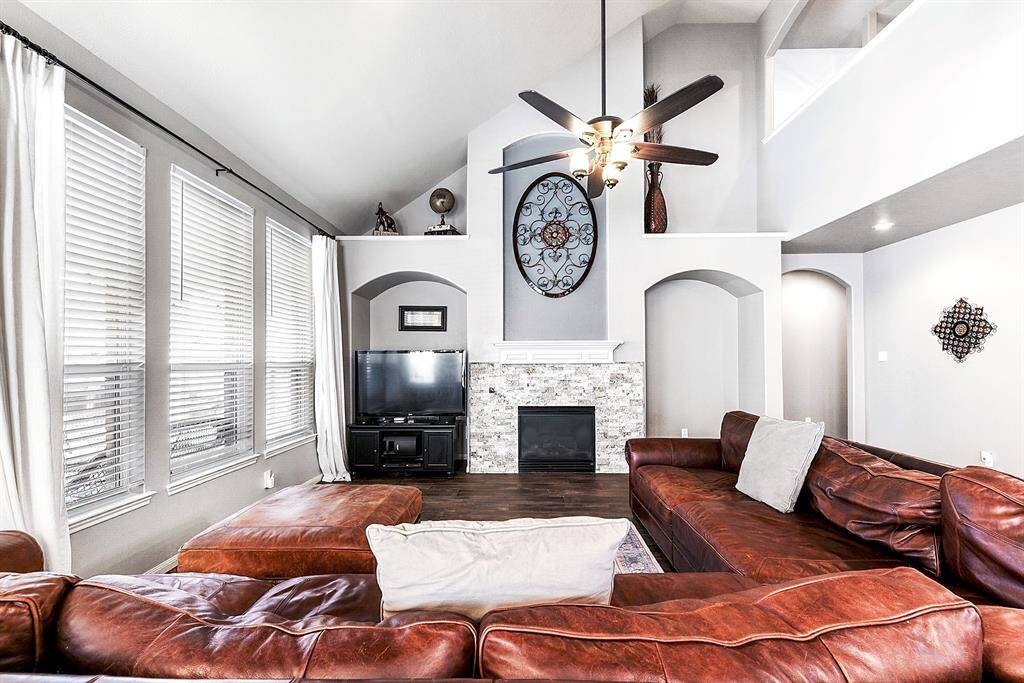 This spacious living room offers versatile space to accommodate any furniture arrangement you may need, providing both comfort and style. It features a gas fireplace with a mosaic tile surround and a white mantle, creating a beautiful focal point. The area above the fireplace is perfect for a TV setup or can be customized with built-in shelving for added storage and display options.