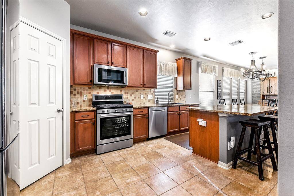 The large kitchen is a chef’s dream, featuring a spacious island with breakfast bar seating, endless granite counter space, and plenty of cabinets with pull-out shelves for optimal storage and convenience.