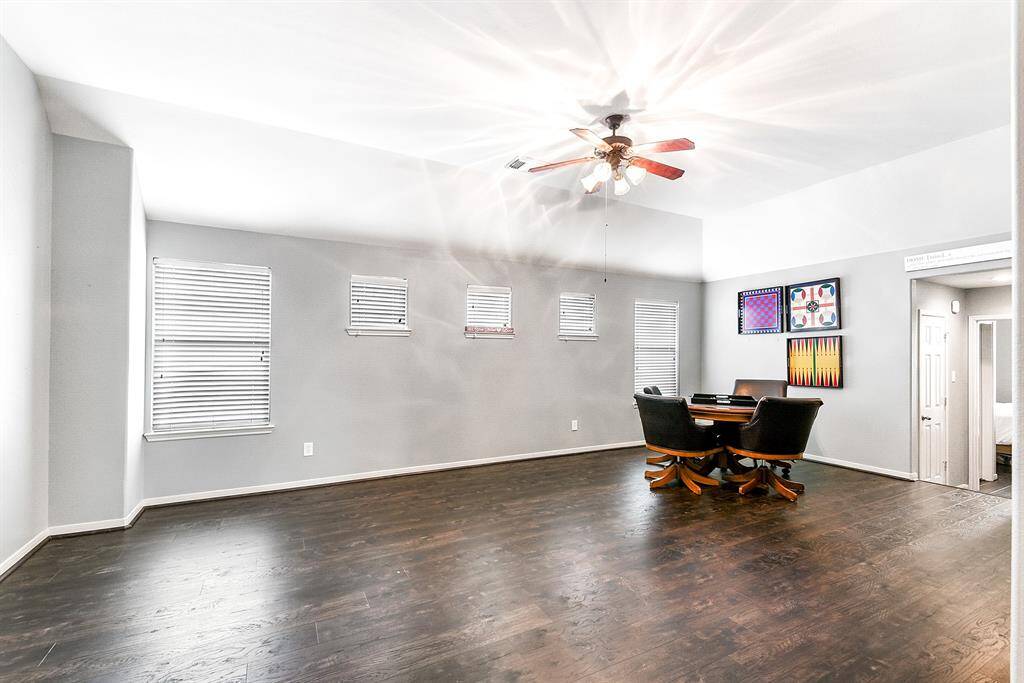 The upstairs area features wood flooring, plenty of windows, and high ceilings, creating a bright and spacious atmosphere. As you enter, you’re greeted by a large game room with ample space to accommodate a card table, pool table, foosball table, and possibly an additional sitting area.
