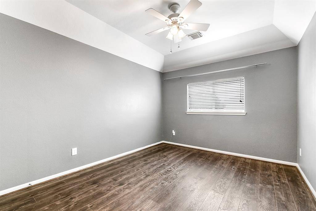 The upstairs guest bedroom features a drop-down ceiling fan, wood flooring, and window treatments.