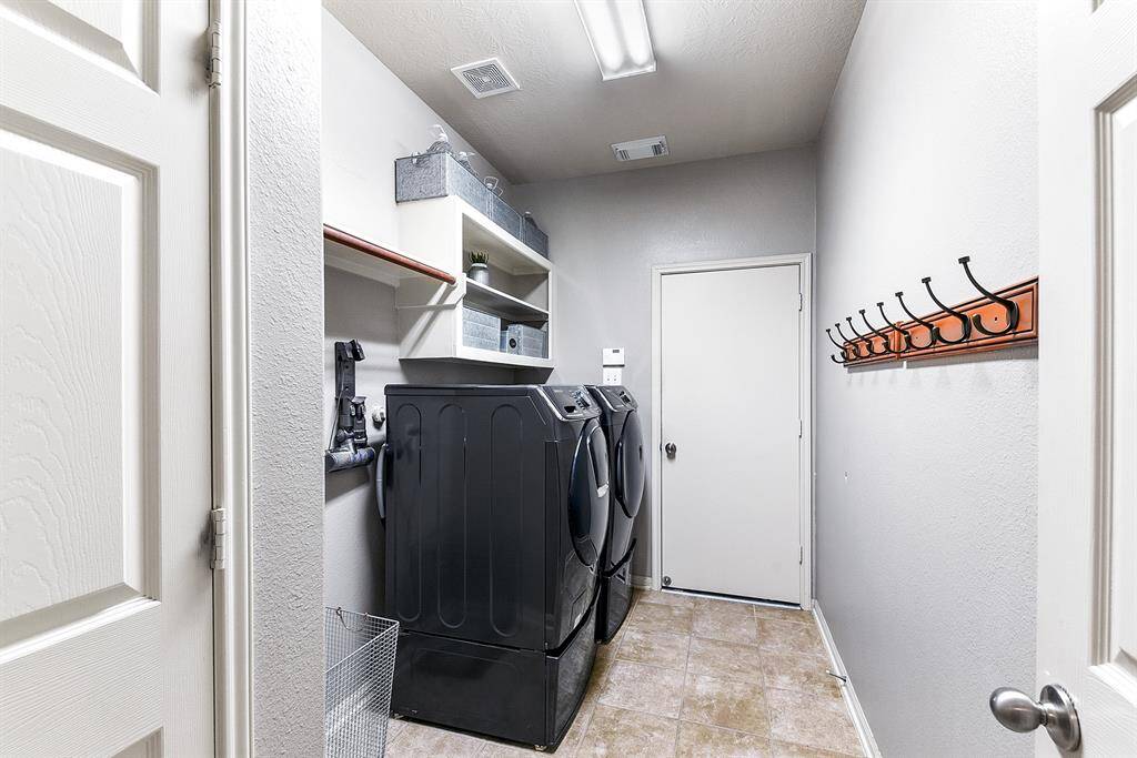 Downstairs features a laundry room that leads into the oversized two-car garage, which includes shelving and a hanging rod. This setup offers convenience and ample storage