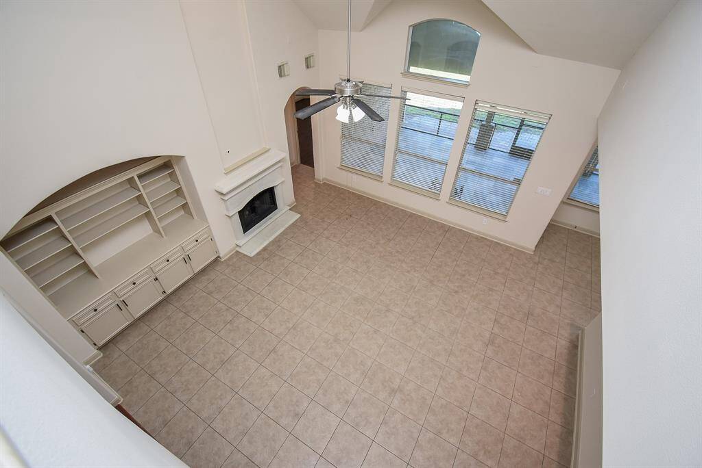 Another view of the living room and its large windows, custom built-ins, and tile flooring.