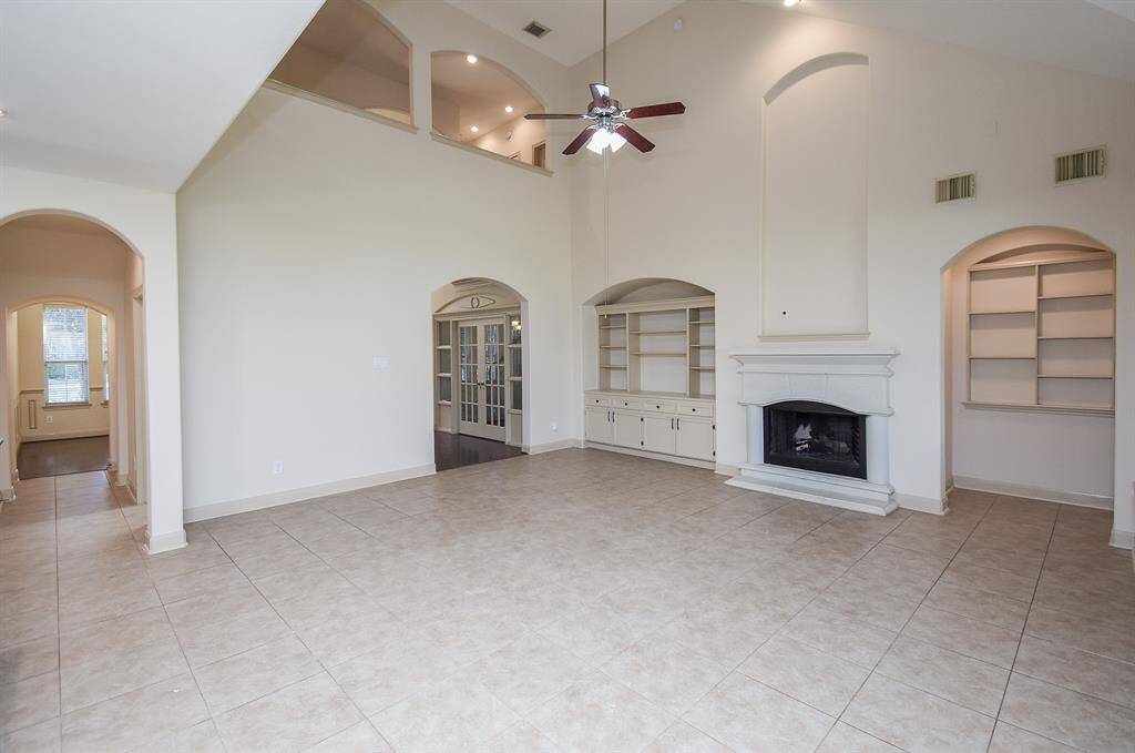 The Living room features high ceilings, a ceiling fan, and a custom fireplace.