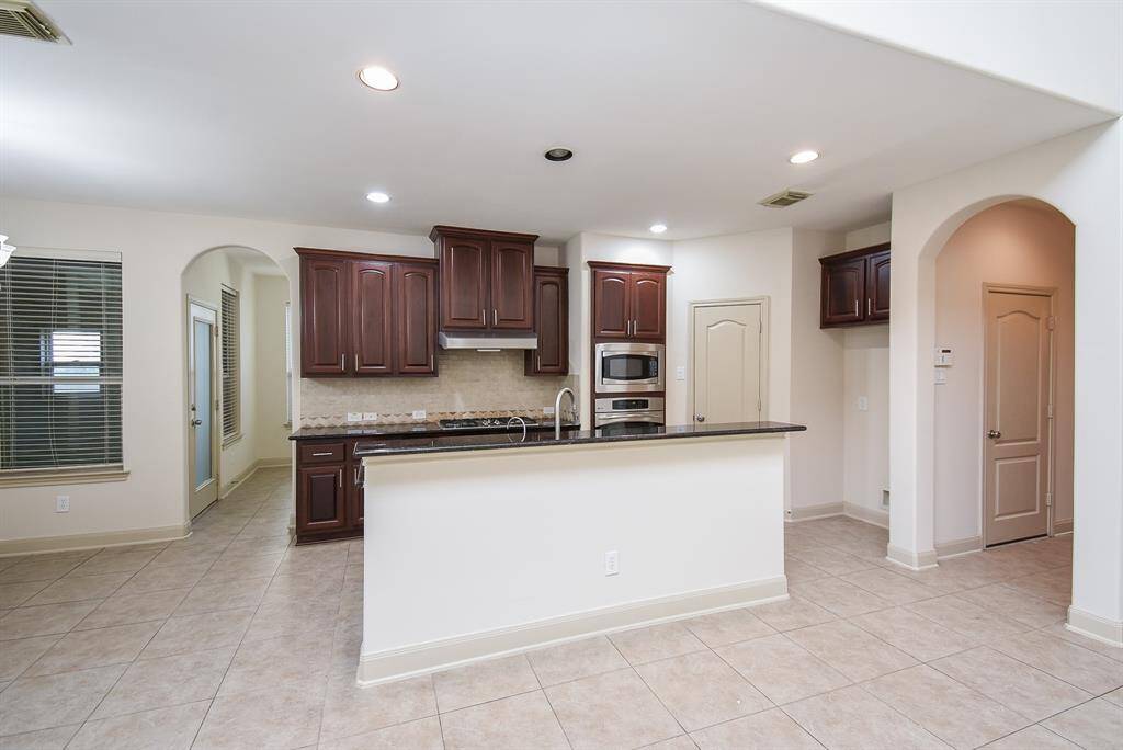 The open kitchen features dark wood cabinetry, modern appliances, and a large island with a breakfast bar.