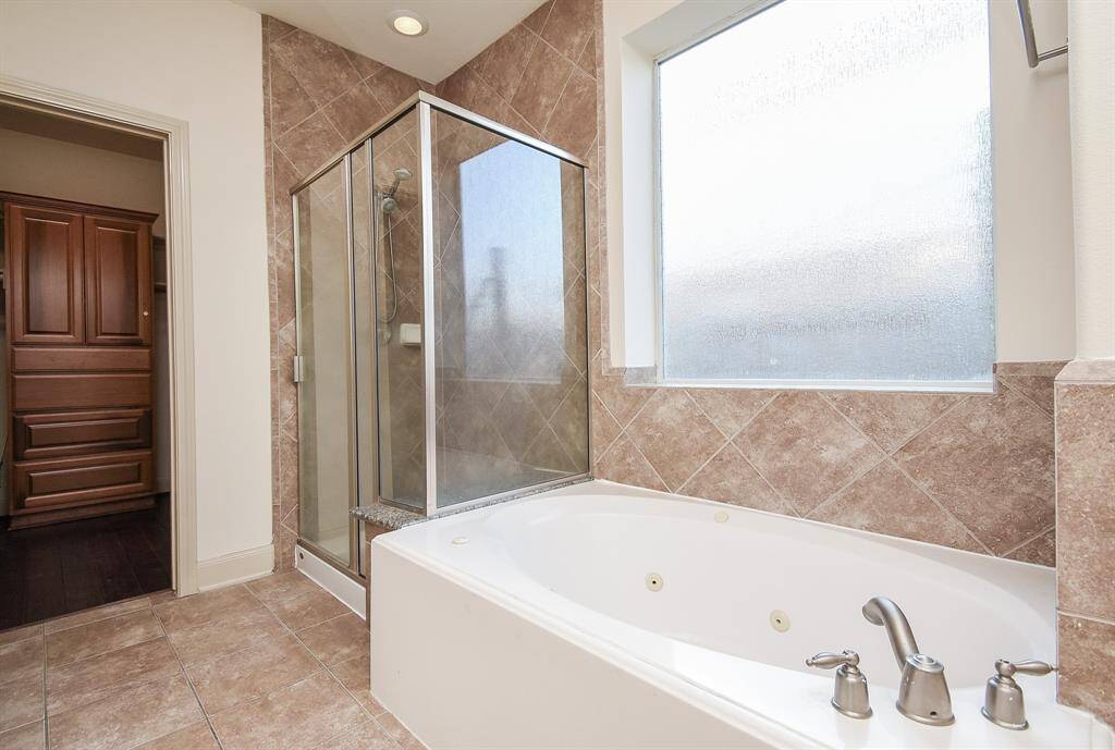 Large soaking tub with sleek fixtures, a separate glass-enclosed shower, and elegant tile work.