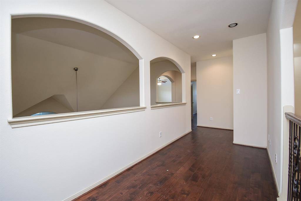 Upstairs Hallway features elegant hardwood flooring and arched openings, providing a view to the living room.