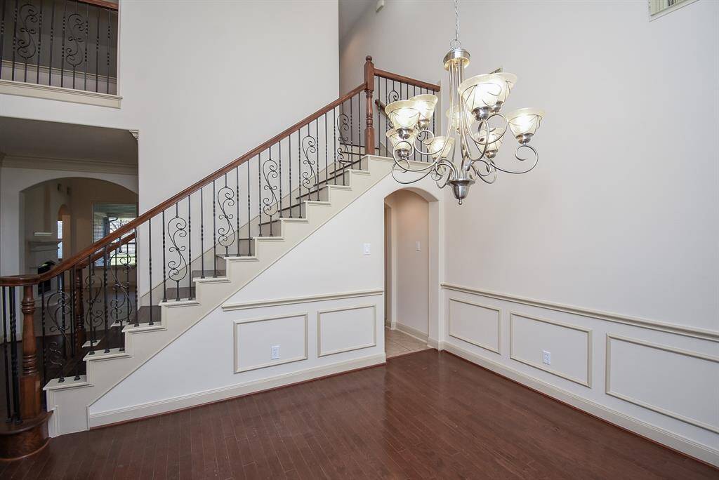 The Entry and Formal dining has high ceilings, wainscoting, and a grand staircase with wrought iron railing, creating a spacious and sophisticated atmosphere.