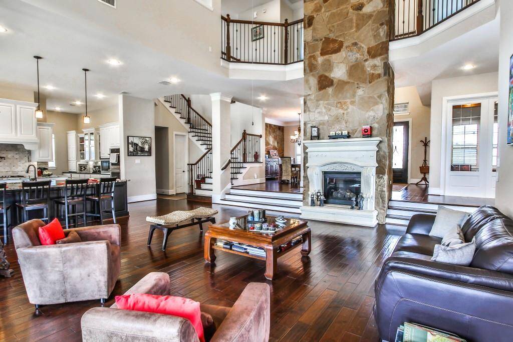 Spacious living room features high ceilings, large windows  and hardwood floors.
