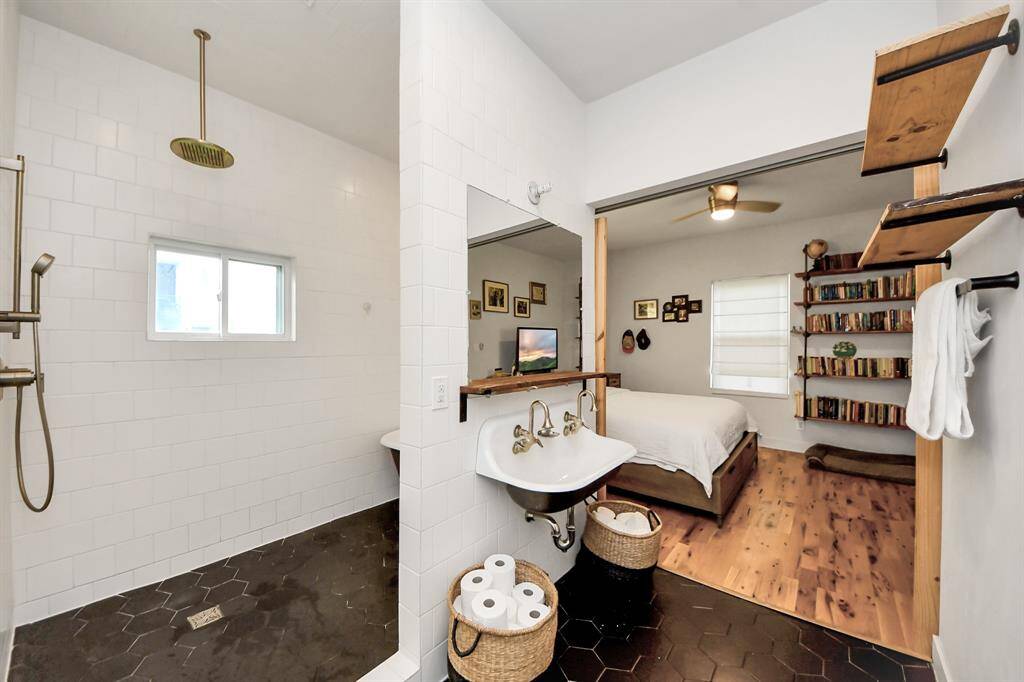 The bathroom features a European style wet area with an impressive walk-in shower with sleek white tiles and a rainfall showerhead, and a claw foot tub!  Complemented by dark hexagonal floor tiles and built-in shelving, creating a seamless flow between the two spaces.