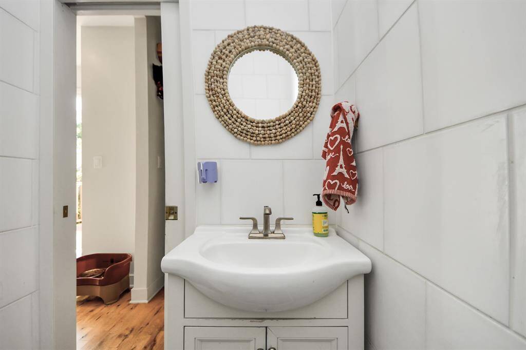 Cozy bathroom with a modern white sink and sleek fixtures. Features a round, textured mirror and vibrant red towel for a pop of color.