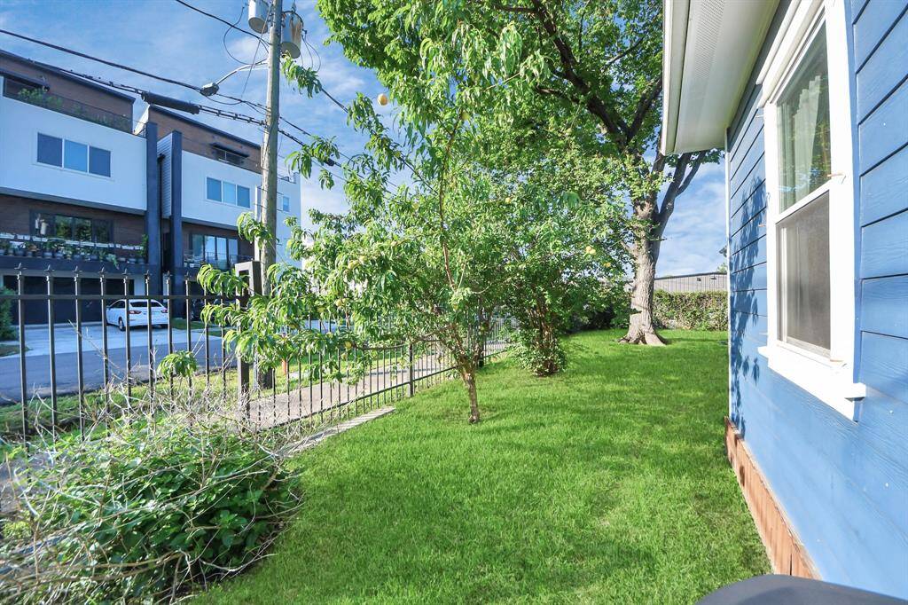 Side yard with lush green grass and a delicious peach tree! Shaded trees to keep you perfectly cool in the summer.