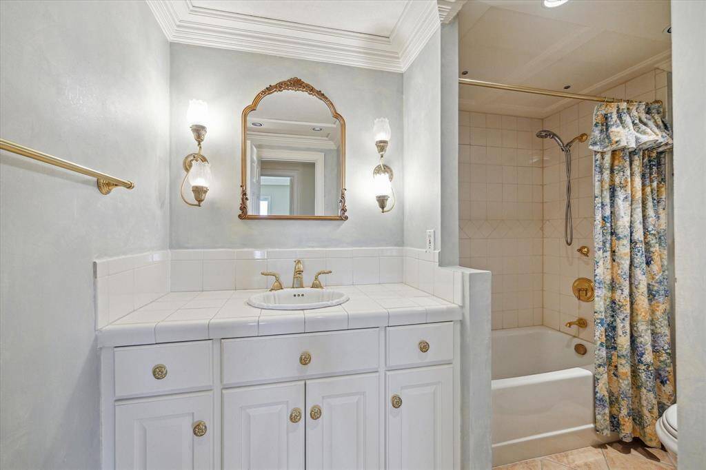 Secondary Hall Bathroom with tile flooring, decorative sconces, Phylrich faucet, & tub/shower combo.