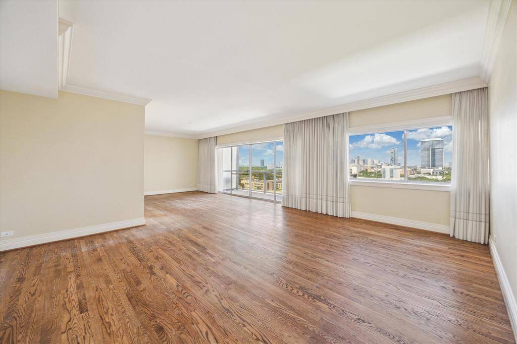 Open Concept Living & Dining Rooms with hardwood flooring, linen drapes, double crown-molding, & tall baseboards.