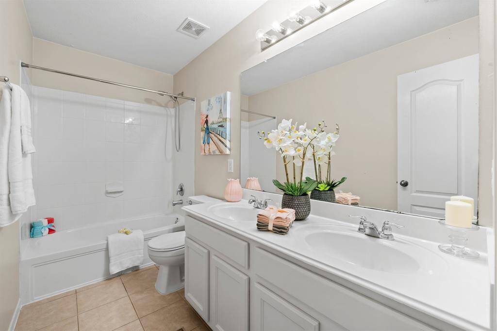 Secondary upstairs bathroom with double sink and white cabinets.