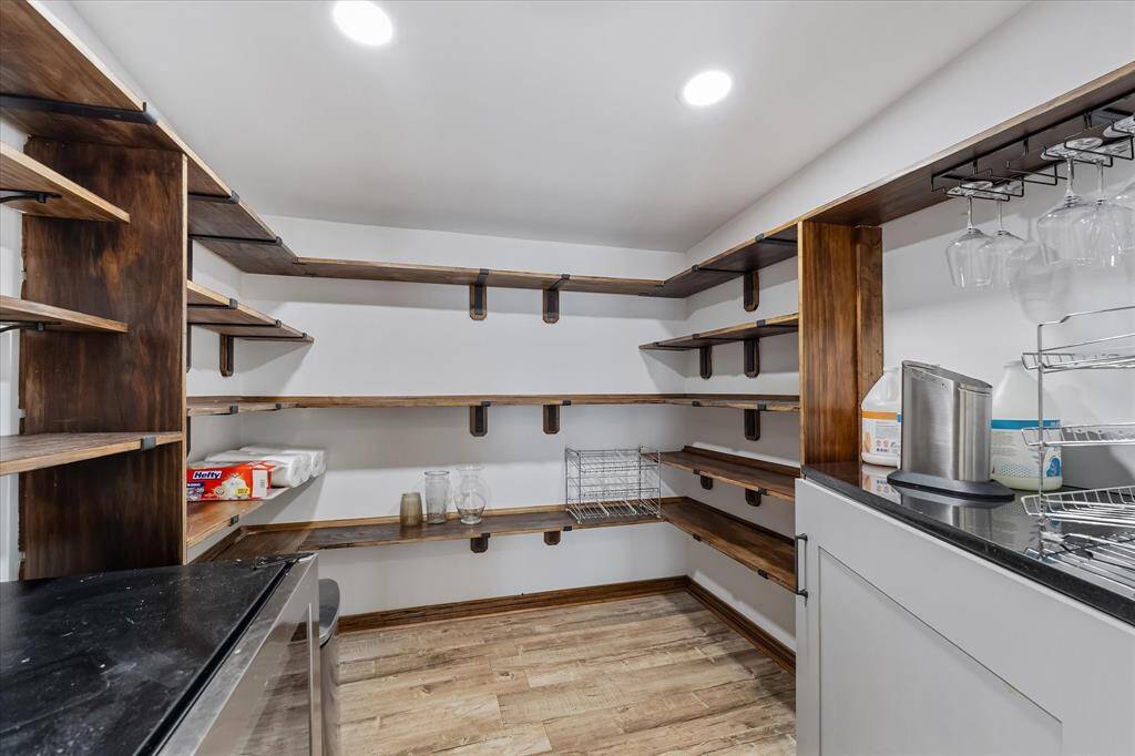 Custom-built walk-in pantry with a sliding barn door, offering ample storage and space for a beverage fridge — the perfect blend of charm and function.