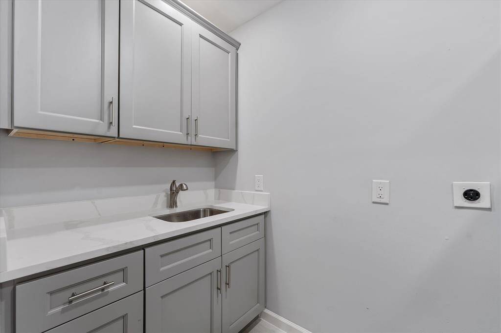 The laundry room is thoughtfully designed with abundant cabinetry, a convenient sink, and plenty of space for storage and organization.
