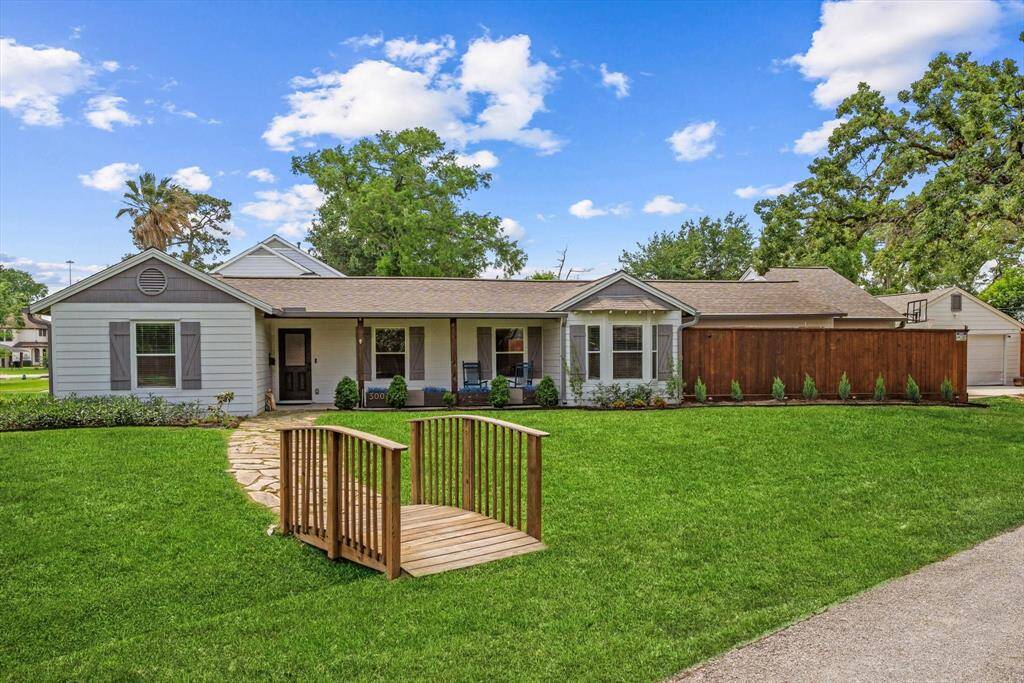 A quaint wooden bridge and paved pathway guide you through the landscaped front yard to a welcoming porch — the perfect entrance to your new home.