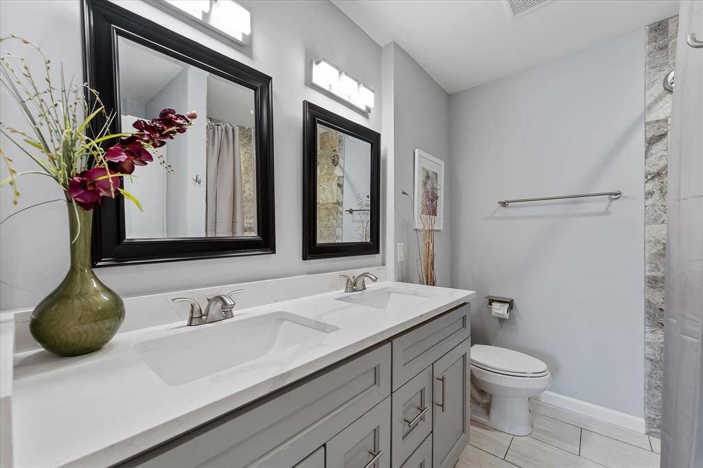 This bathroom features quartz countertops, a dual vanity, and a clean, modern design — perfect for busy mornings or winding down at the end of the day.