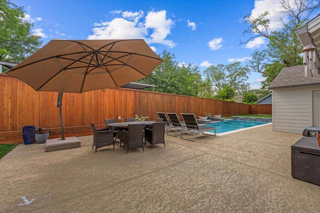 New heated pool with waterfall feature, fire pits, and recently poured concrete decking — a backyard built for entertaining and enjoying every season.