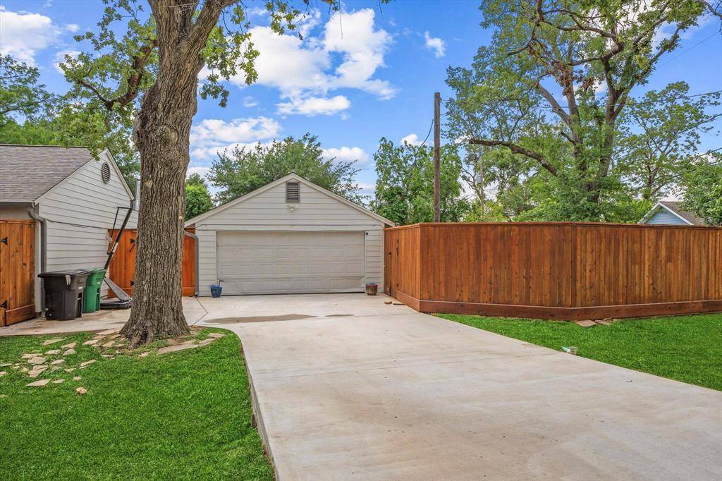 Detached 2-car garage with sleek epoxy flooring, plus extended driveway space and a mounted basketball hoop — great for extra parking or a quick game of hoops.