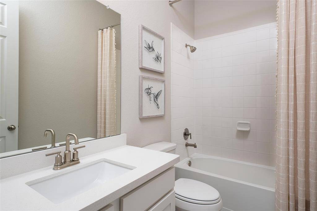 The secondary bath features tile flooring, white cabinetry and light countertops and a shower/tub combo. Perfect for accommodating any visiting family and friends.