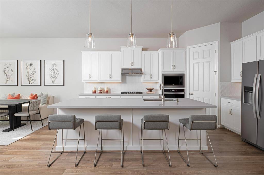 This light and bright kitchen features a large quartz island, white cabinets, a large sink overlooking your family room, recessed lighting, and beautiful backsplash.